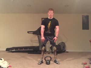 Step 1 - feet outside shoulders, bell centered between feet. Knees are bent, butt is back, posture is starting to lean forward.
